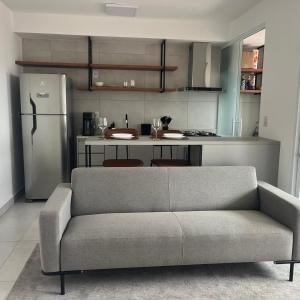 a living room with a couch and a kitchen at Apartamento confortável – perto do centro de Bauru in Bauru