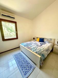 a bedroom with a bed and a window and a rug at La Casetta al mare in Stintino