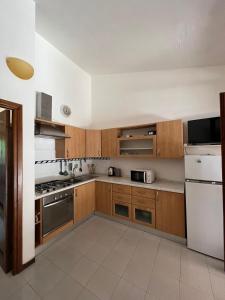 a kitchen with wooden cabinets and a white refrigerator at La Casetta al mare in Stintino +12 photos