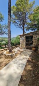 a walkway leading to a stone building with two trees at Le Masdemoiselle Mazet in Salernes