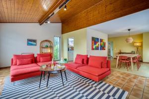 un salon avec des canapés rouges et une table dans l'établissement Alta House - Central Ferney and Family-Friendly, à Ferney-Voltaire