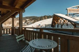 een tafel en een stoel op een terras met een skipiste bij CHALET TEKA LES GETS - Appartement Chery in Les Gets