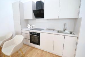 a kitchen with white cabinets and a sink and a chair at Apartment Grace Family in Vienna +34 photos