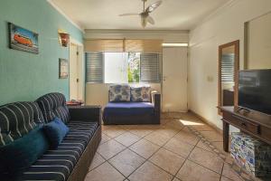 a living room with a couch and a chair and a television at 1E - Pe na Areia da Praia do Tombo, 3 Quartos, Ar Cond, 2 WC, 1 vaga e Roupas de Cama in Guarujá