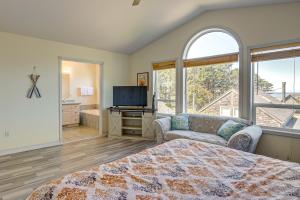 Un dormitorio con una cama y un televisor y una ventana. en Walk to Shore Home with Deck in Rockaway Beach!, en Rockaway Beach