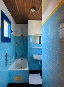 La salle de bains est pourvue de carrelage bleu, d'une baignoire et d'un lavabo. dans l'établissement Hotel Arcantis Le Voltaire, à Rennes