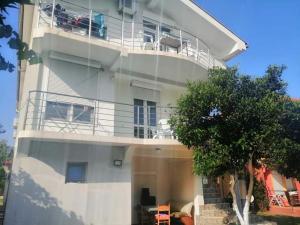 a large white building with a balcony and a tree at Vila Bula 1 in Donji Štoj