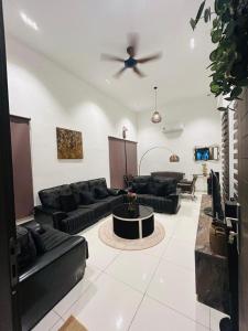 a living room with black couches and a ceiling fan at Ethereal Ipoh Homestay in Ipoh