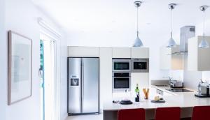 a white kitchen with a stainless steel refrigerator at Spacieuse villa de vacances avec piscine privée in Souraïde
