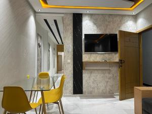 a dining room with a glass table and yellow chairs at Beautiful, well-equipped apartment in Martil
