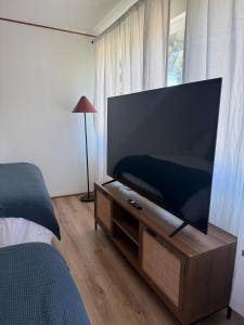 TV de pantalla plana en un soporte de madera en un dormitorio en Cozy Private Room in DTLA, en Los Ángeles
