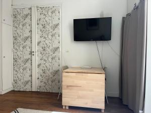 a room with a tv on a wall with a dresser and a door at Charming Studio Apartment with Patio Passerelle in Paris