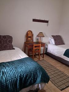 a bedroom with two beds and a desk with a lamp at Erin Guesthouse and B&B in Bergville