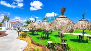 a group of tables and chairs with straw umbrellas at Villa Palmera in Las Casicas