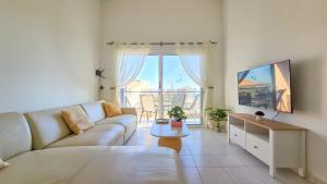 a living room with a couch and a tv at CSS Cosmic Smart Superior Sea View Tala in Tala