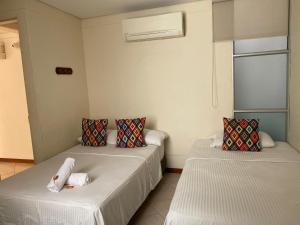 a room with two beds and a window at Hotel Tierra Santa Santa Fe de Antioquia in Santa Fe de Antioquia
