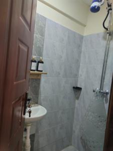 Un baño con ducha, lavabo e inodoro. en Yegen Homes, en Munyu