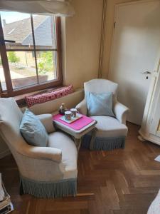 ein Wohnzimmer mit zwei Stühlen und einem Tisch in der Unterkunft Cosy Cottage Rooms near Autobahn A2 & Hannover in Barsinghausen