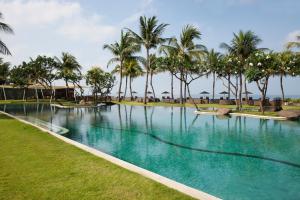 ein großer Pool mit Palmen im Hintergrund in der Unterkunft The Samaya Seminyak Bali in Seminyak