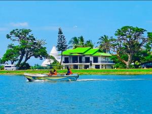 two people in a boat in the water in front of a house at Tissa Yala Lake View Hotel in Tissamaharama