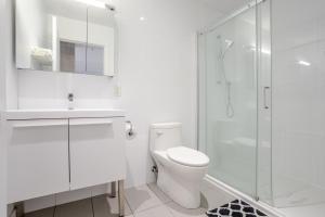 ein weißes Badezimmer mit Toilette und Dusche in der Unterkunft Modern Heritage Stay Upscale 2BR in Old Port in Montreal