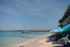 a beach with chairs and umbrellas and the ocean at CARDUMEN Arte y Cocina in Playa Blanca