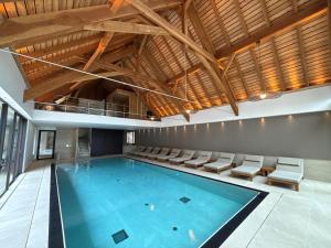 an indoor swimming pool with chairs and a ceiling at Hotel Restaurant L'Ami Fritz in Ottrott
