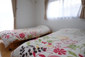 Cottage Kutsuroki في ياكوشيما: سريرين يجلسون بجانب بعض في غرفة النوم