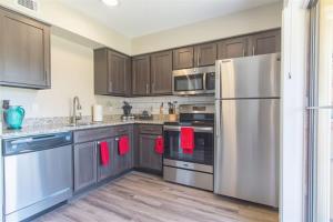 a kitchen with stainless steel appliances and wooden cabinets at Boulevard Stays Tranquil 1BR King Suite Pool Gym Parking 02 in Dallas