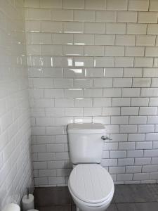 ein weißes Bad mit einem WC und einer weißen Ziegelwand in der Unterkunft Love Breeze Cottage  + 64 Fotos