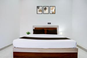 a bedroom with a large white bed with black pillows at Hotel O The King Heaven in Etāwah +22 photos