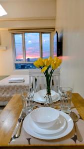 a table with two plates and a vase of yellow flowers at Bella Suite Netflix Pool Great View in Manila