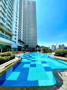 a large blue swimming pool in front of a tall building at Bella Suite Netflix Pool Great View in Manila