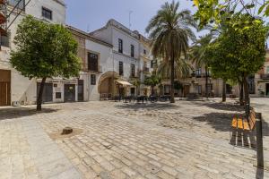 a cobblestone street in a town with trees and buildings at Allo Apartments Ático Jaramago Parking Centro 1 Hab in Jerez de la Frontera