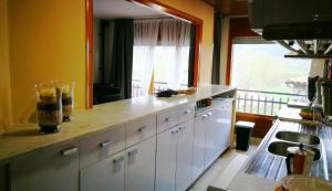 a kitchen with white cabinets and a large window at Apartamento Ideal familias en Bellver in Bellver de Cerdanya