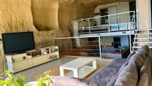 een woonkamer met een bank en een tv bij La Baume du Delà in Saint-Chamas