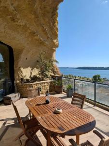 een houten tafel en stoelen op een balkon met uitzicht op de oceaan bij La Baume du Delà in Saint-Chamas