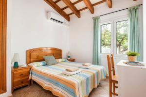 a bedroom with a bed and a window at Villa Airosa by Villa Plus in Cala'n Porter