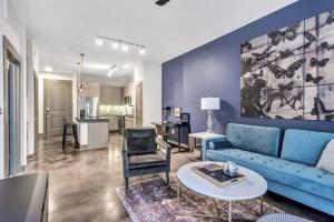 a living room with a blue couch and a table at Boulevard Stays Elegant 1BR Pool Gym Parking in Richardson