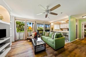 a living room with a green couch and a kitchen at Sandpiper 120A in Princeville