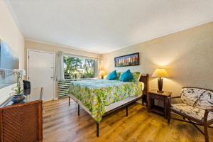 a bedroom with a bed and a chair and a window at Sandpiper 120A in Princeville +18 photos