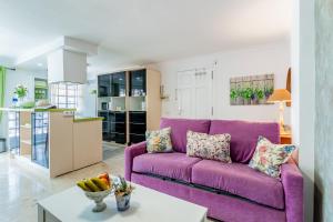 un salon avec un canapé violet et une table dans l'établissement Encantador piso en centro de Puerto de la Cruz con gran terraza, à Puerto de la Cruz