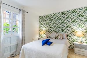 une chambre avec un lit avec un papier peint tropical dans l'établissement Encantador piso en centro de Puerto de la Cruz con gran terraza, à Puerto de la Cruz
