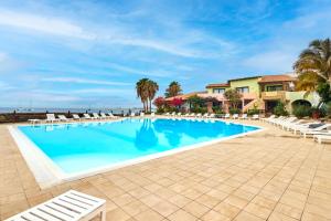 a large swimming pool with chairs and palm trees at Porto Antigo Hotel BB in Santa Maria