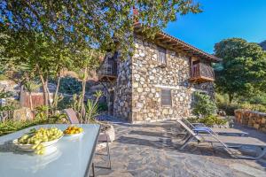 a table with a bowl of fruit in front of a house at Velanos Villas in Kefálion