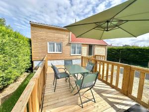 una terrazza con tavolo, sedie e ombrellone di BERCK-PLAGE - 4 Hébergements insolites Tiny House de 2 à 18 personnes a Berck-sur-Mer