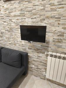 a television on a brick wall with a couch at Chiabrera11 Aquarium - Genovainrelax in Genova +7 photos