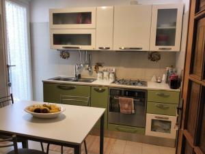 a kitchen with green cabinets and a table with a bowl of fruit at Chiaro di Luna in Budoni