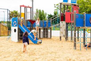 two children playing on a playground in the sand at Mobilhome 4 étoiles - Parc aquatique - eeiaeh in Saint-Jean-de-Monts