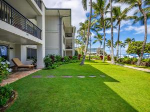 a lawn in front of a building with palm trees at 4-Bed Villa 104 at Turtle Bay in Kahuku